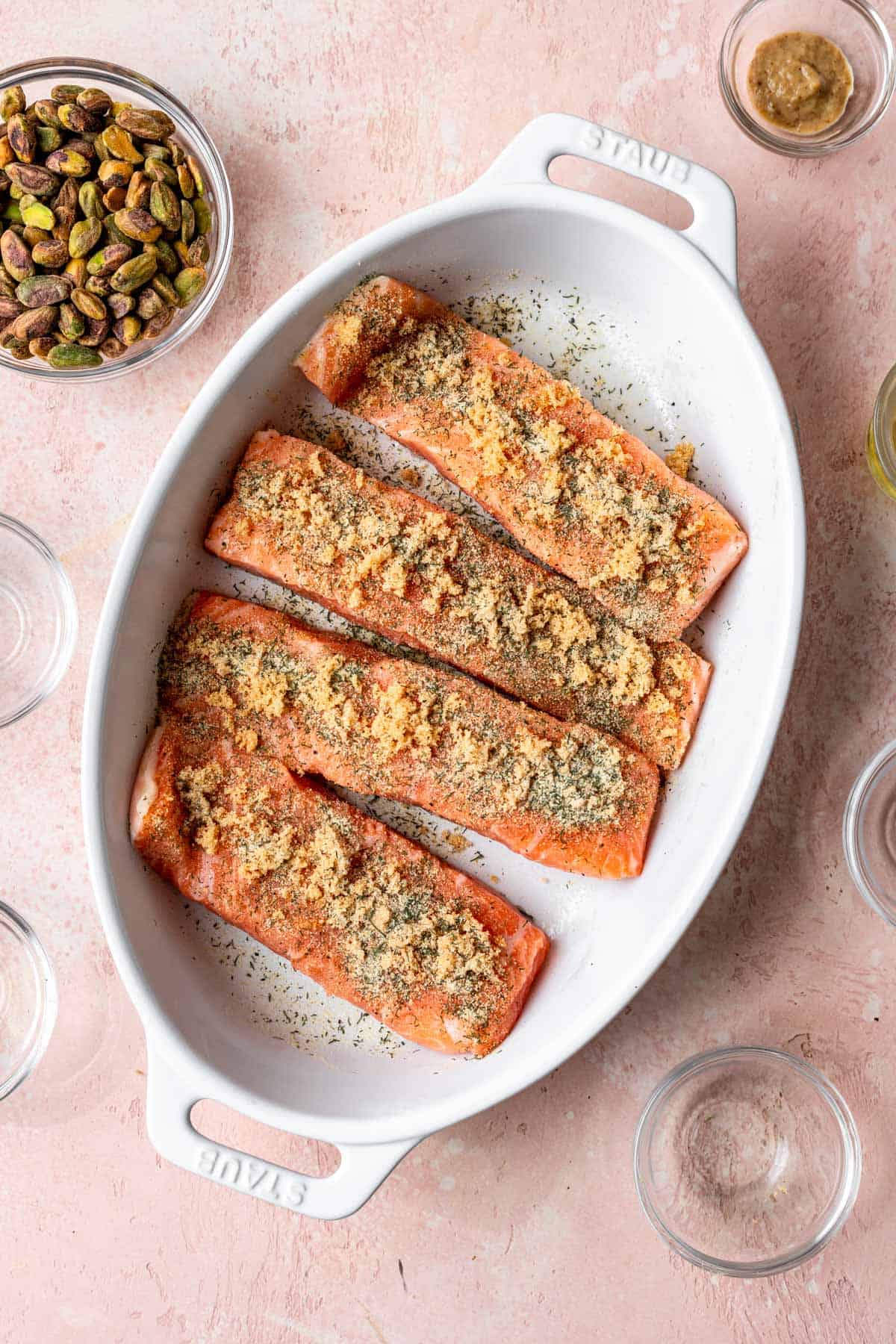 4 filets of salmon seasoned in a baking dish.