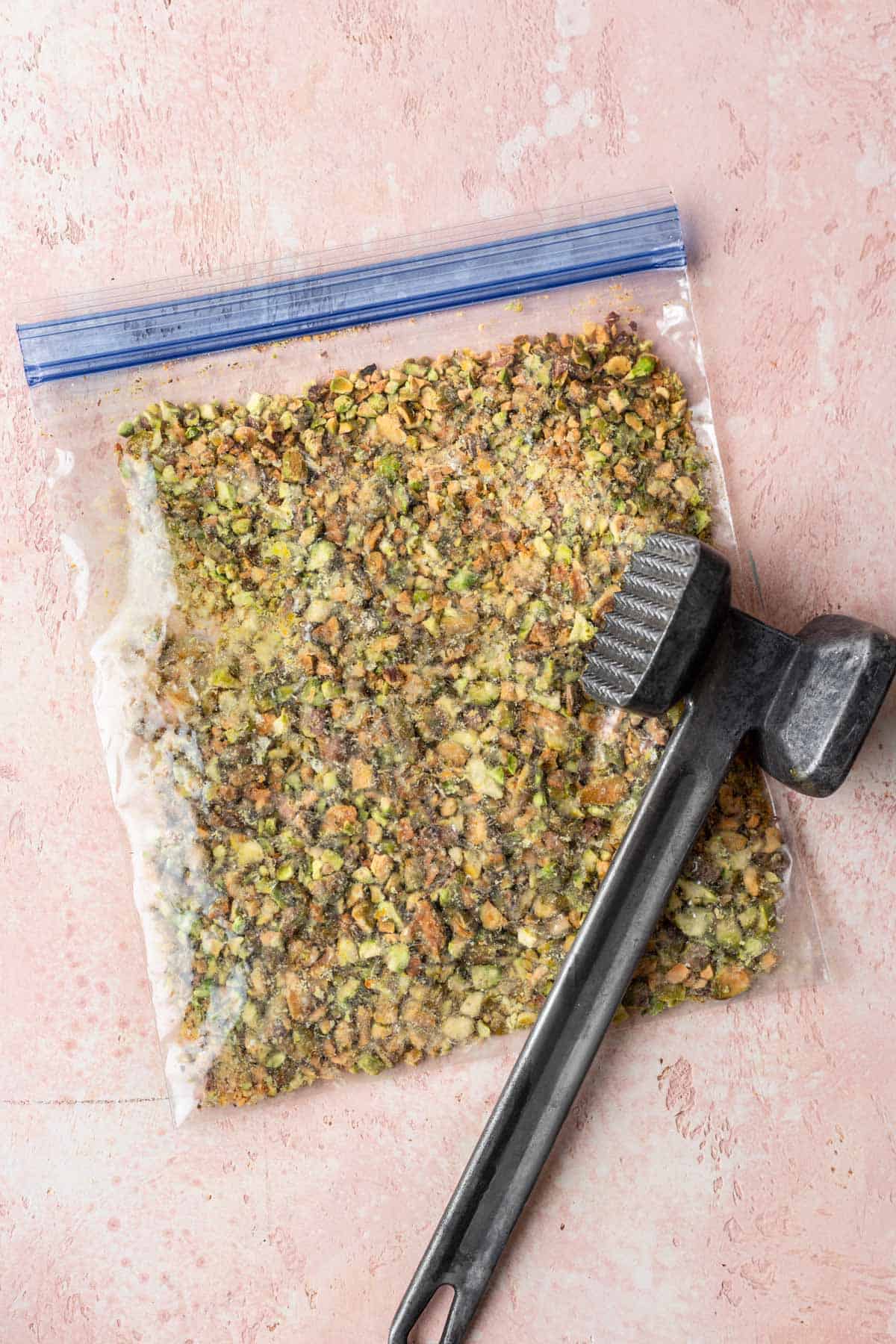 Pistachios in a zip top bag crushed with a meat mallet.