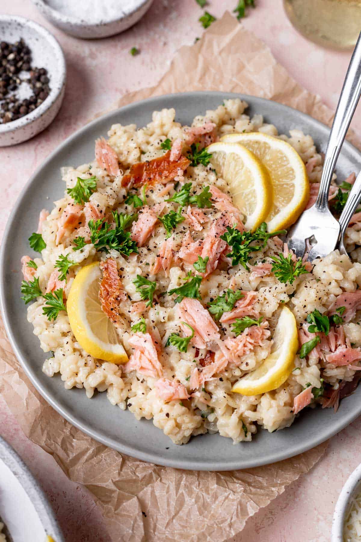 Risotto topped with smoked salmon, sliced lemons, and fresh parsley.