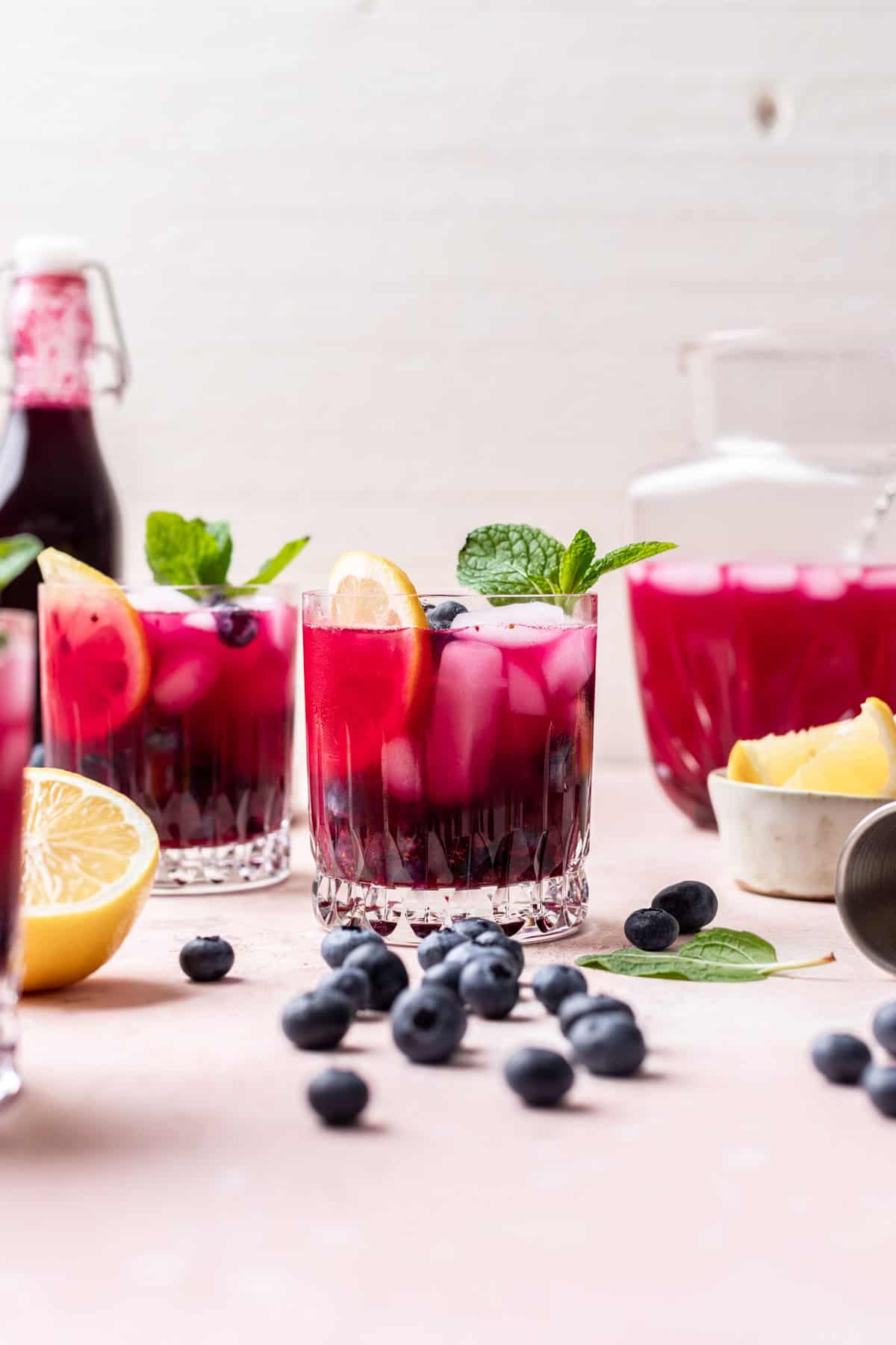 Blueberry vodka lemonade in glass cups garnished with mint and lemon slices.