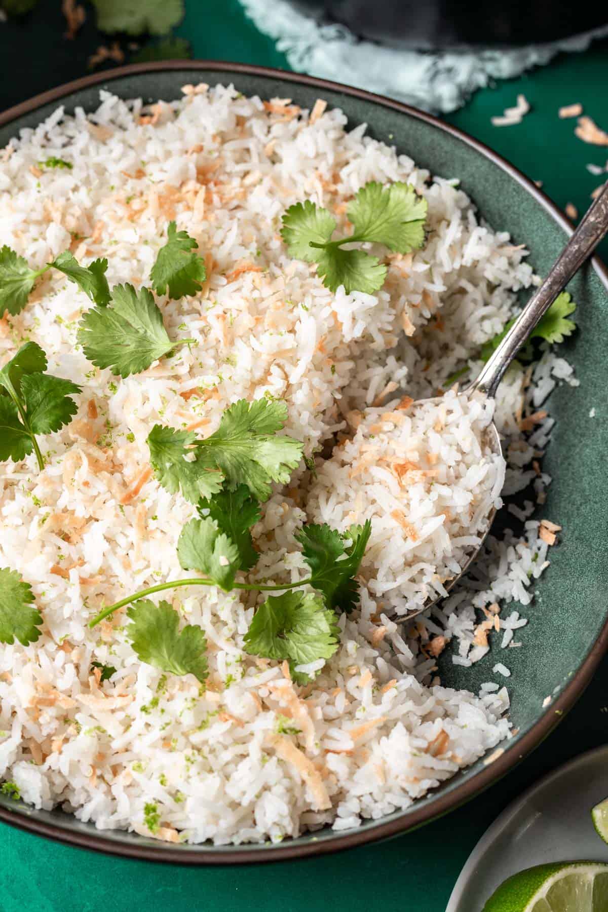 Coconut lime rice in a serving bowl with a serving spoon.