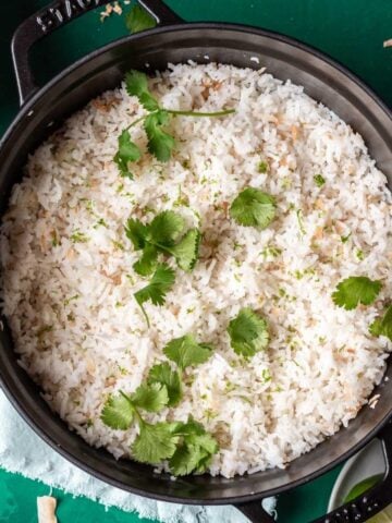 Coconut lime rice in a black pot with cilantro on top.