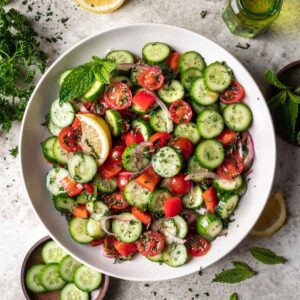 Jerusalem salad in a serving bowl garnished with fresh mint.