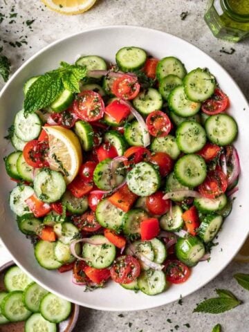 Jerusalem salad in a serving bowl garnished with fresh mint.