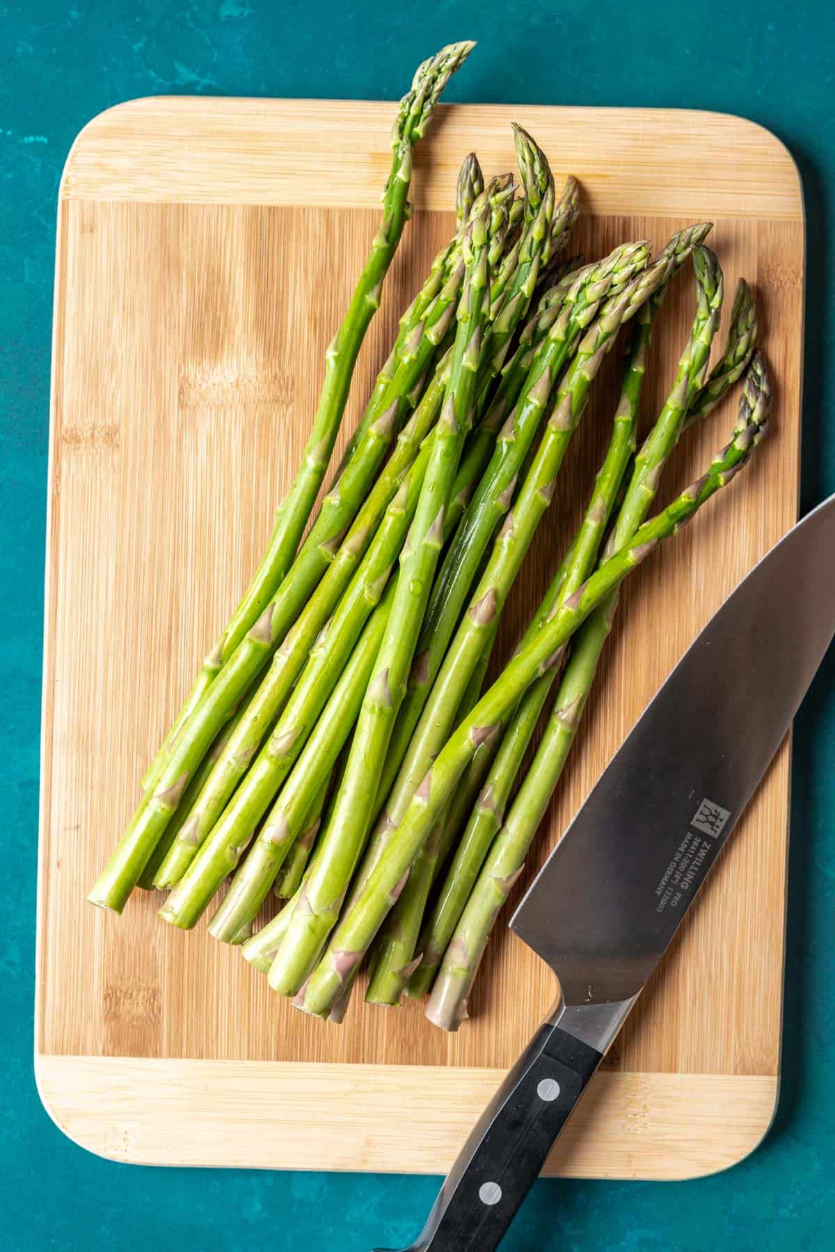 Asparagus on a cutting board with a knife.