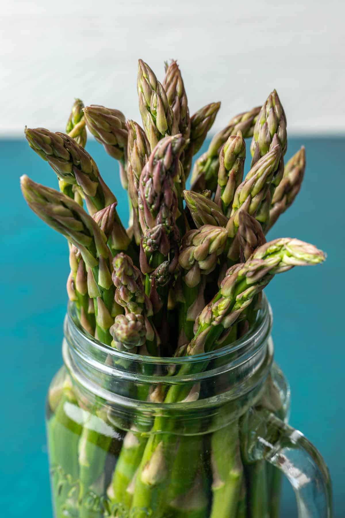Tops of asparagus sticking out of a jar.