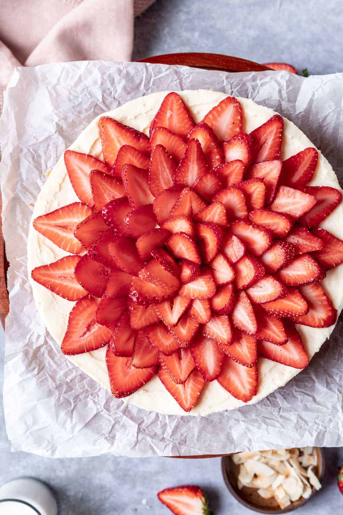 Sliced strawberries in concentric circles on top of a vanilla bean white chocolate mousse cheesecake.