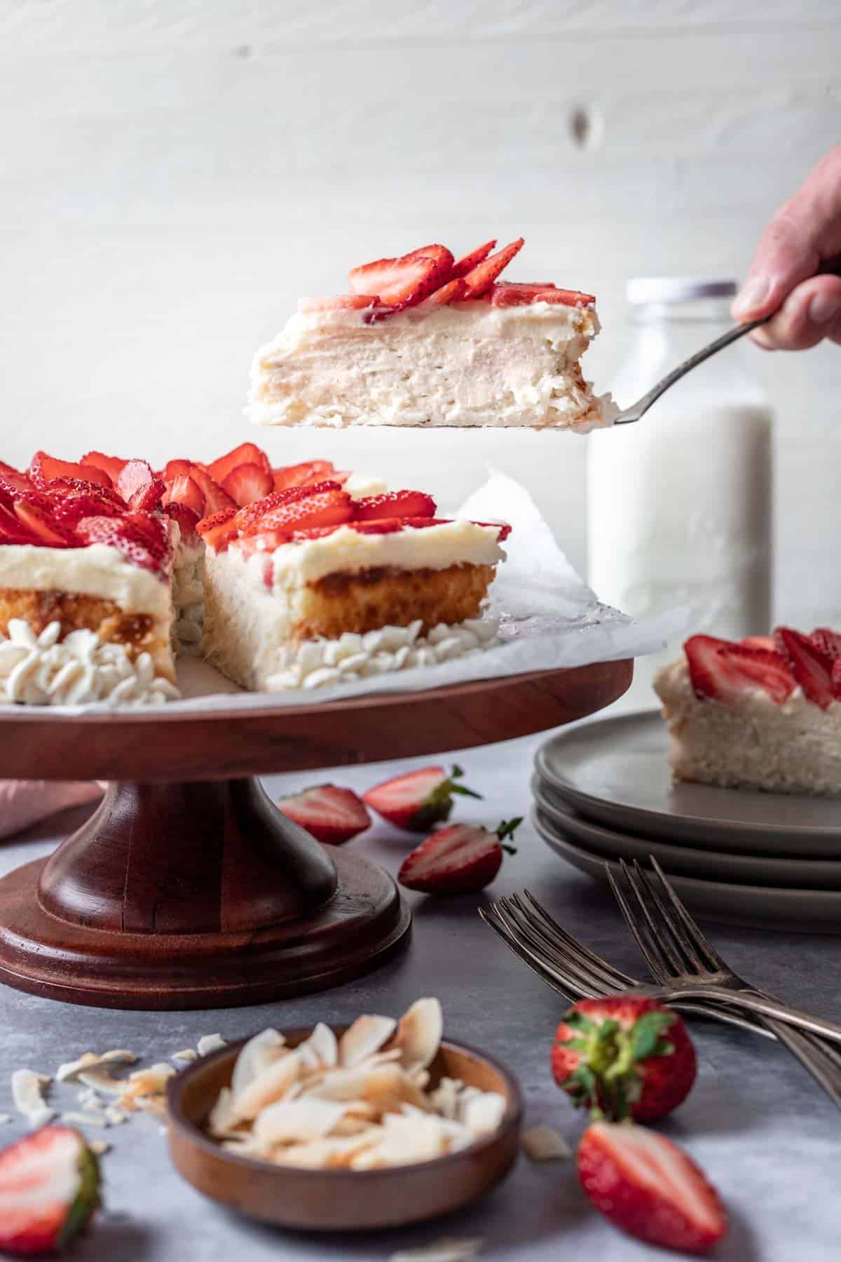 A spatula scooping up a piece of kosher for passover cheesecake topped with sliced strawberries.