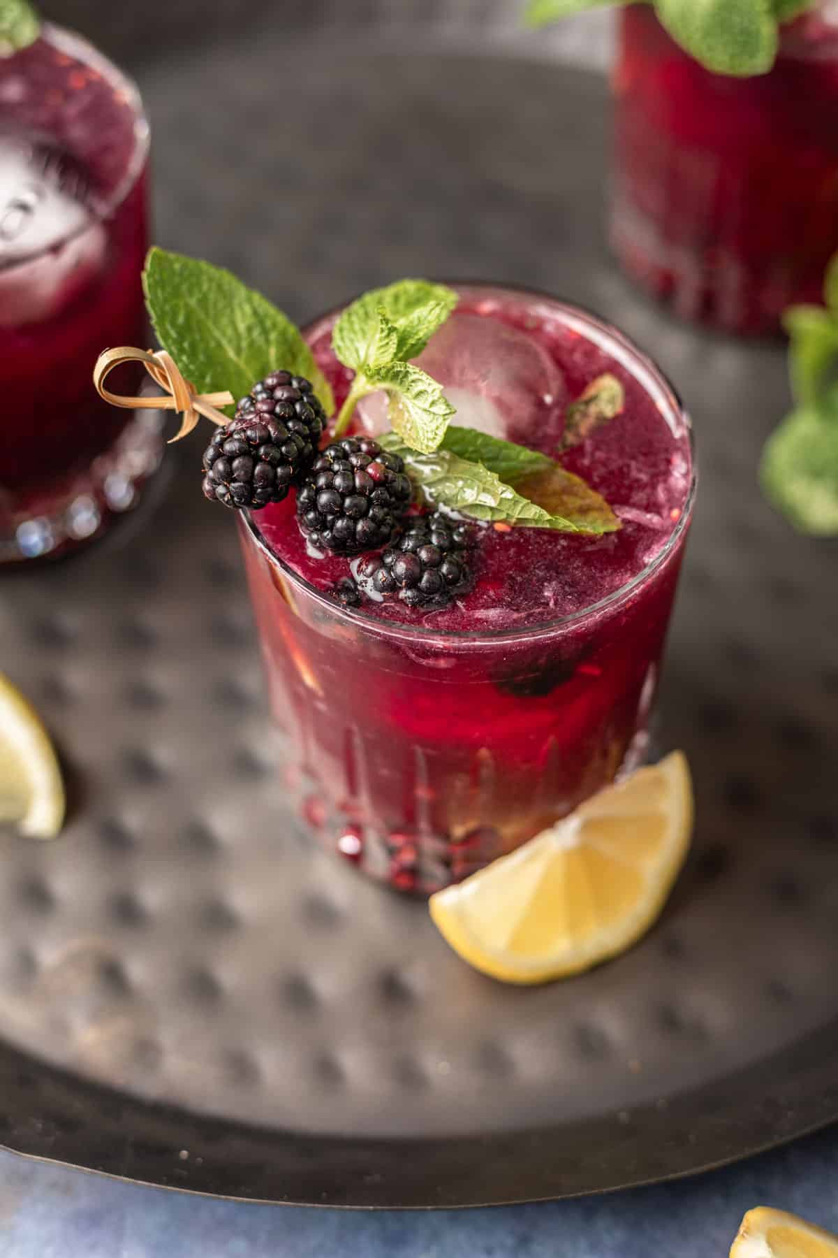 Blackberry bourbon smash garnished with blackberries and fresh mint in a clear glass.