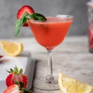 Strawberry basil gin smash garnished with a strawberry slice and basil.