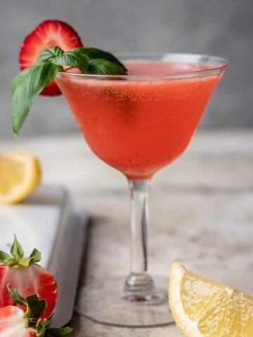 Strawberry basil gin smash garnished with a strawberry slice and basil.