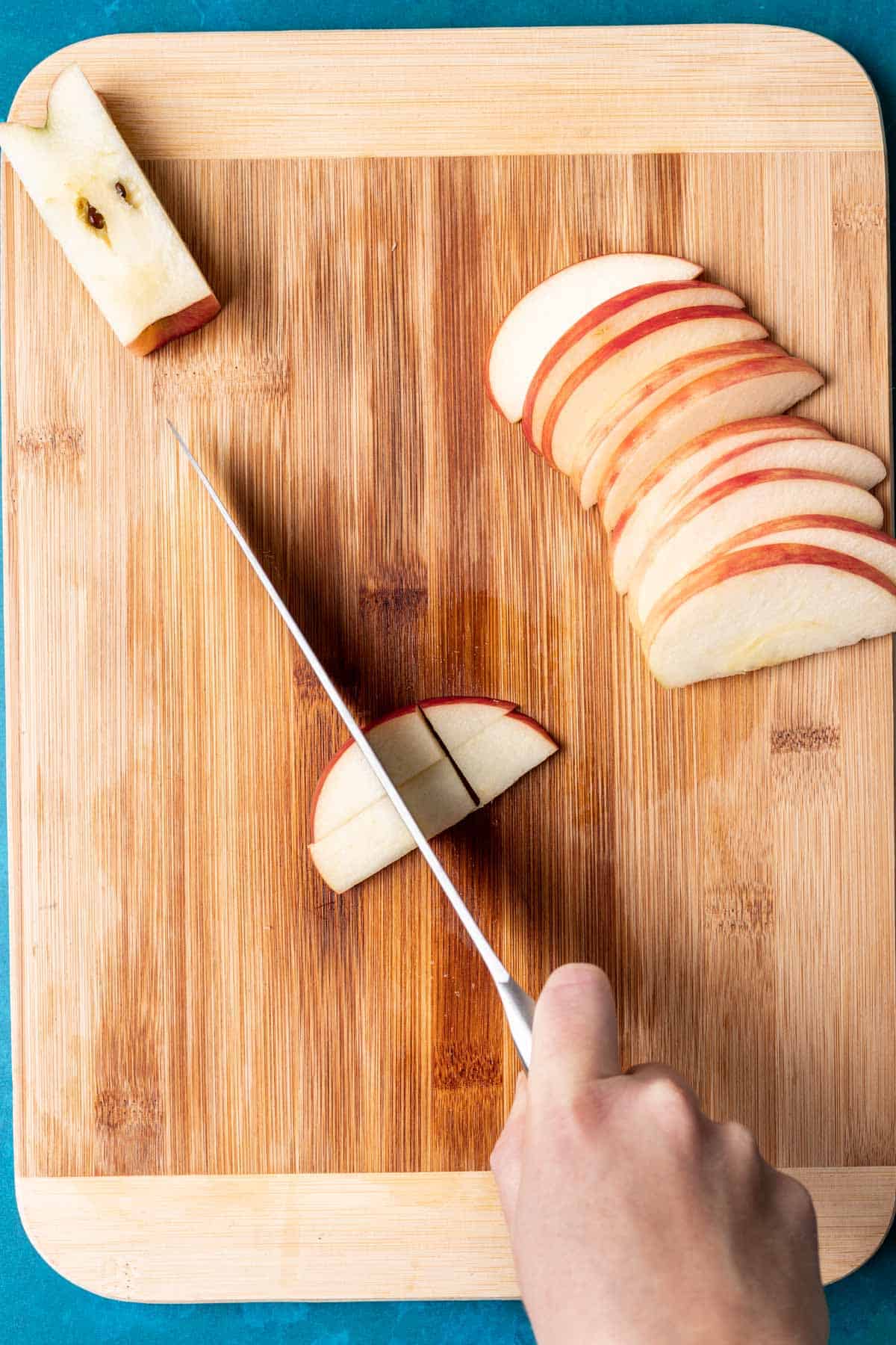 A knife cutting slices of apples into smaller pieces.