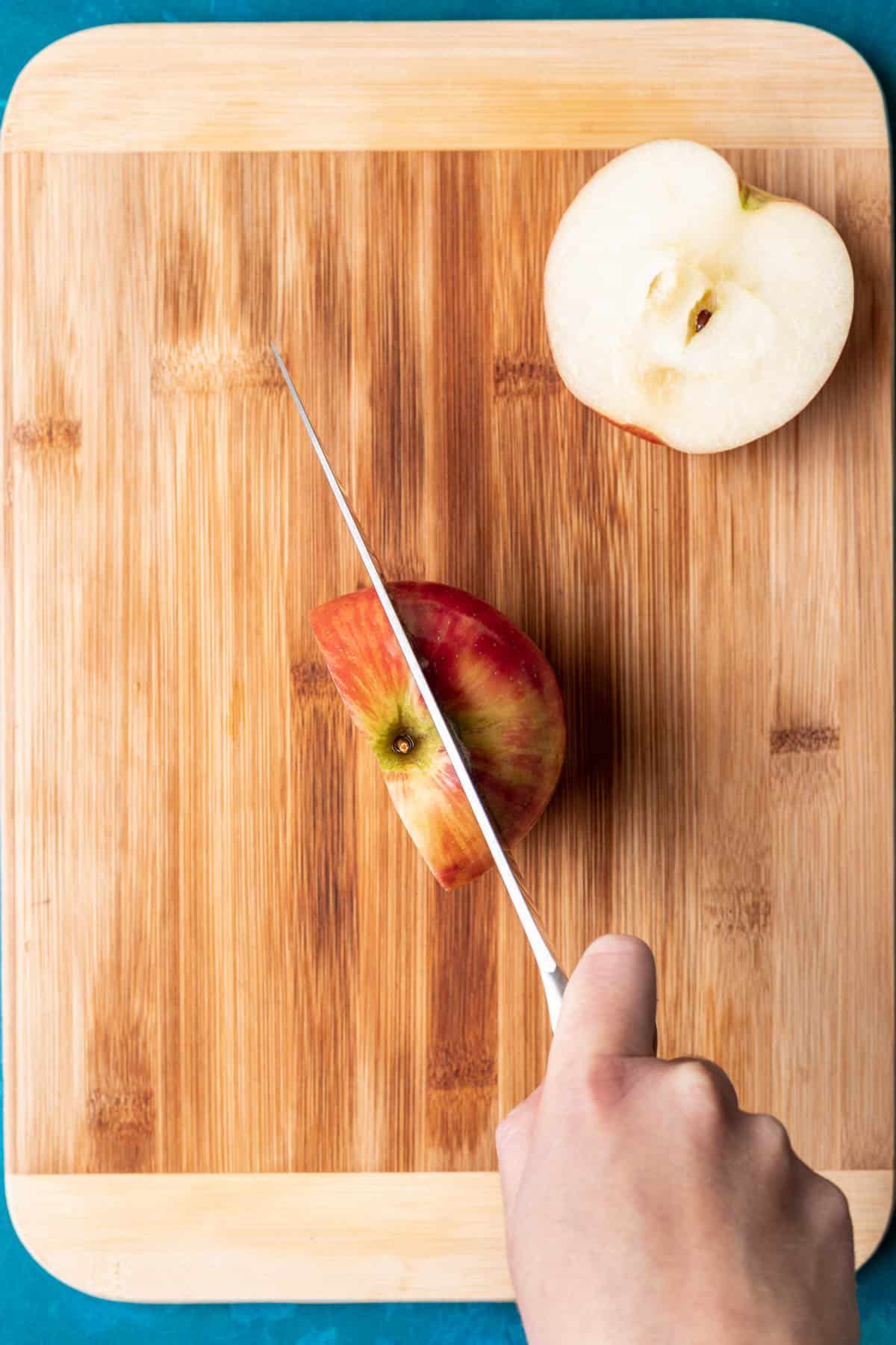 A knife cutting the sides off the apple.