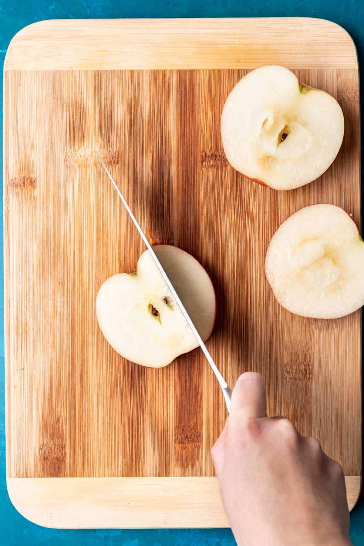 A knife cutting the remaining sides off an apple.
