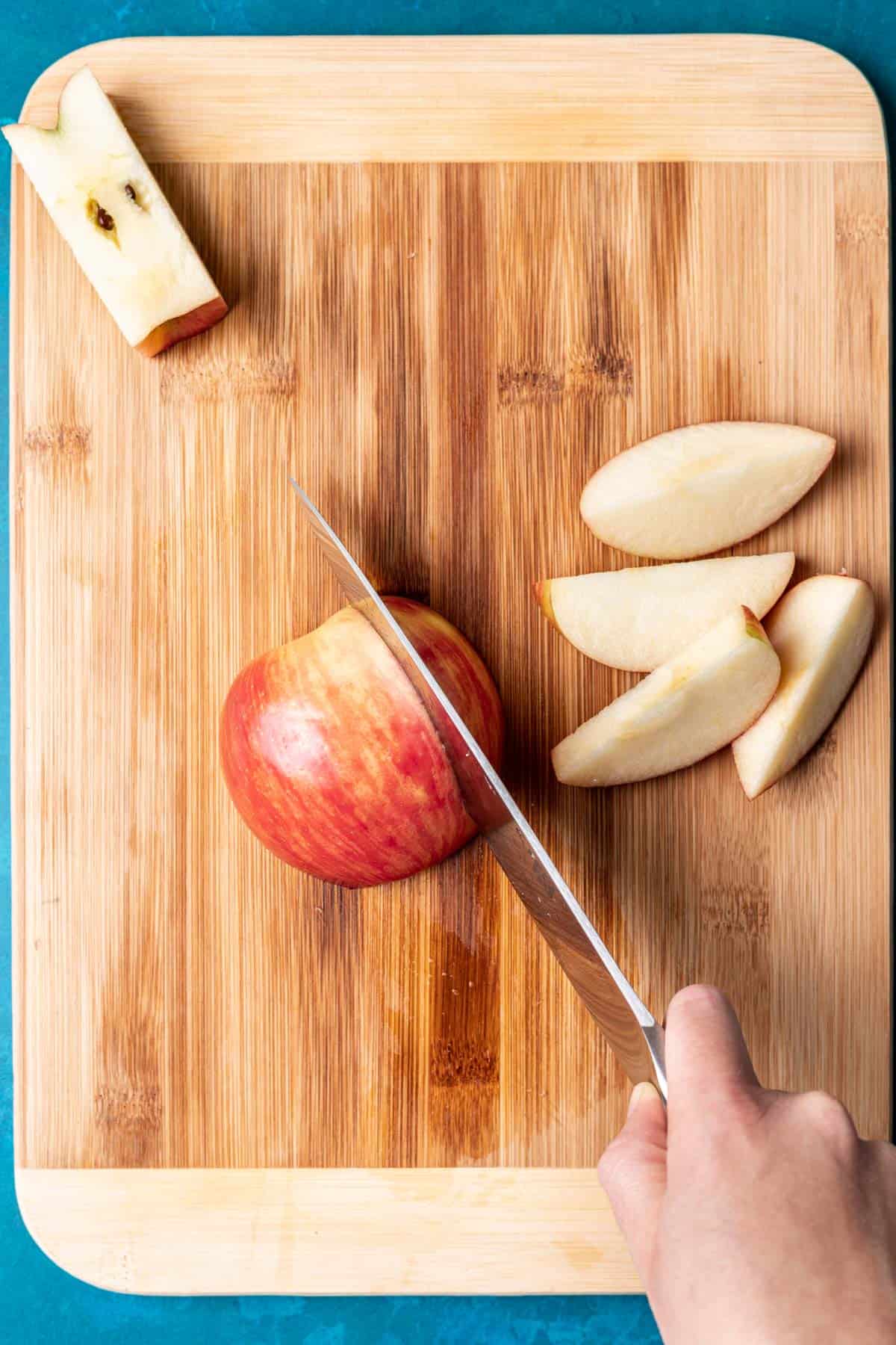 A knife cutting an apple into wedges.