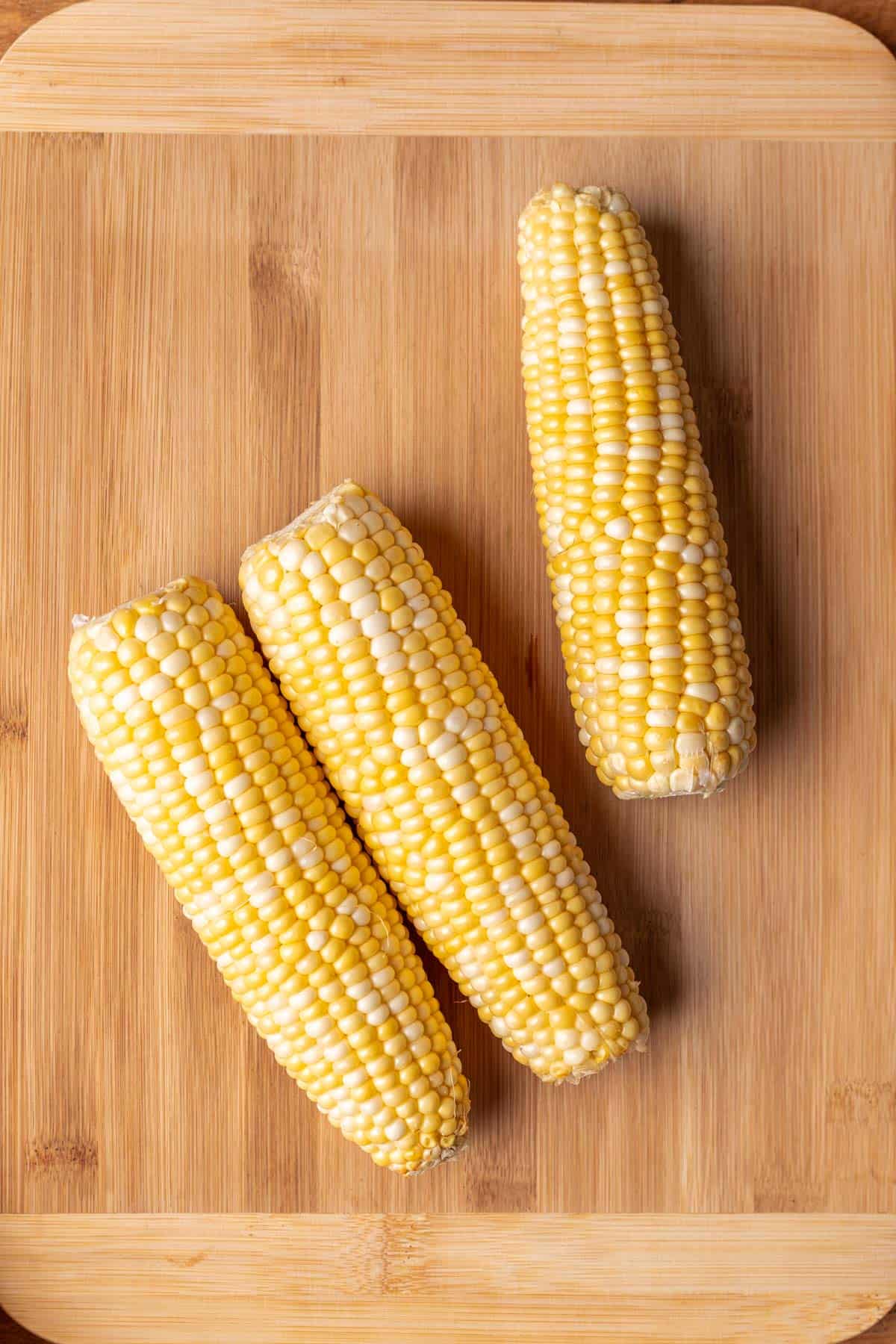 Corn on the cob on a wooden cutting board.