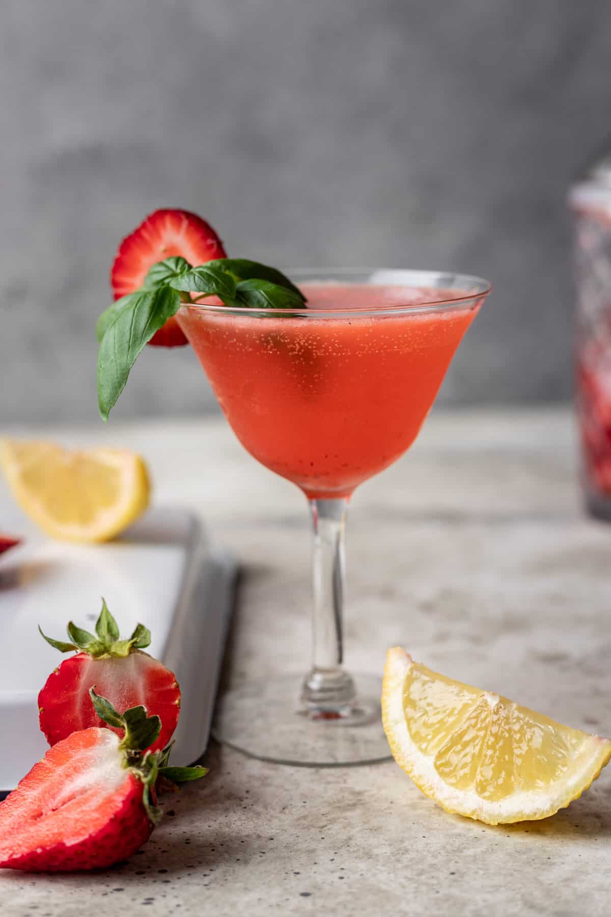 Strawberry basil gin smash in a fancy glass with strawberries and basil.