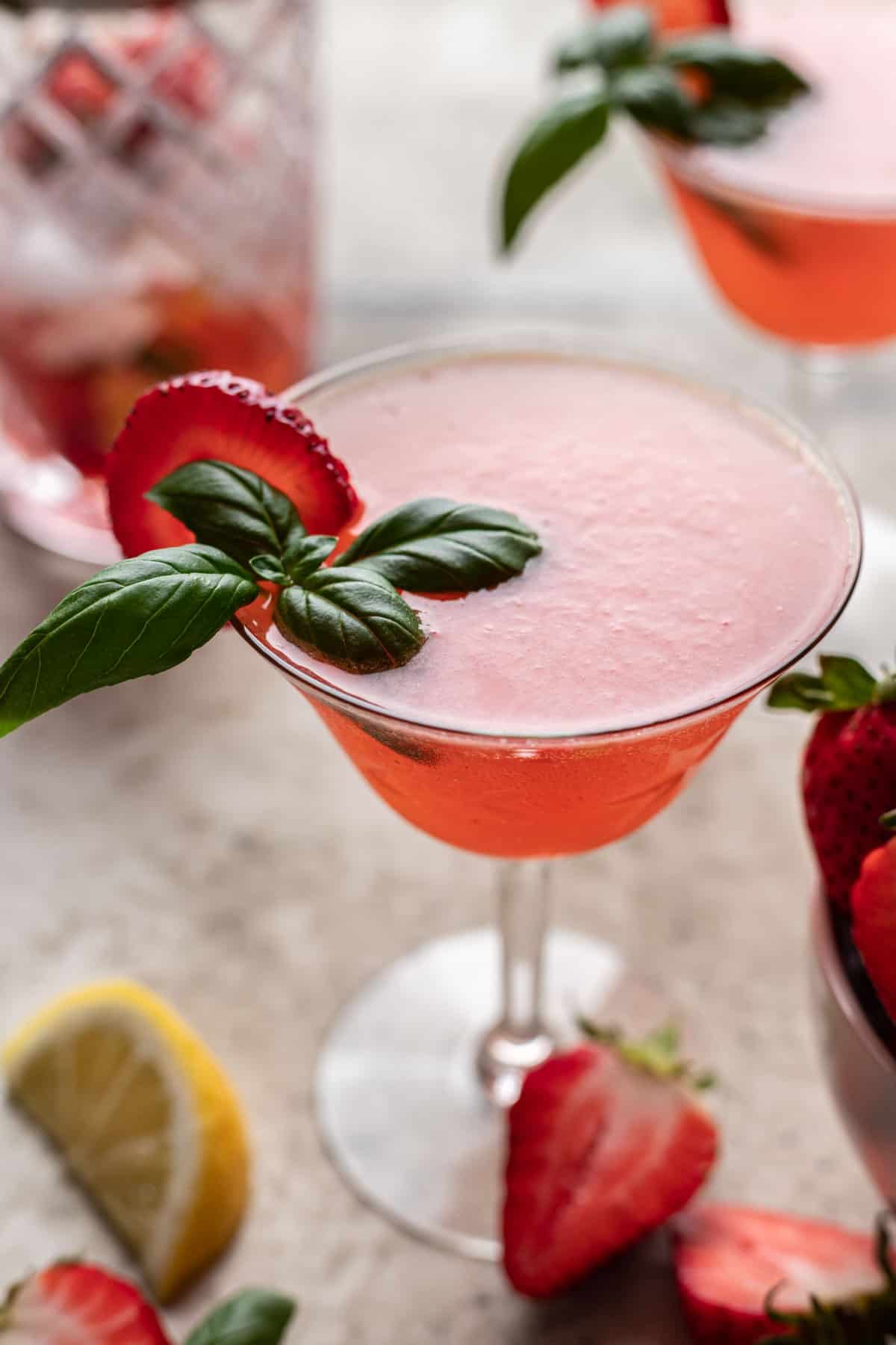 Strawberry basil gin smash garnished with a strawberry slice and basil leaves.