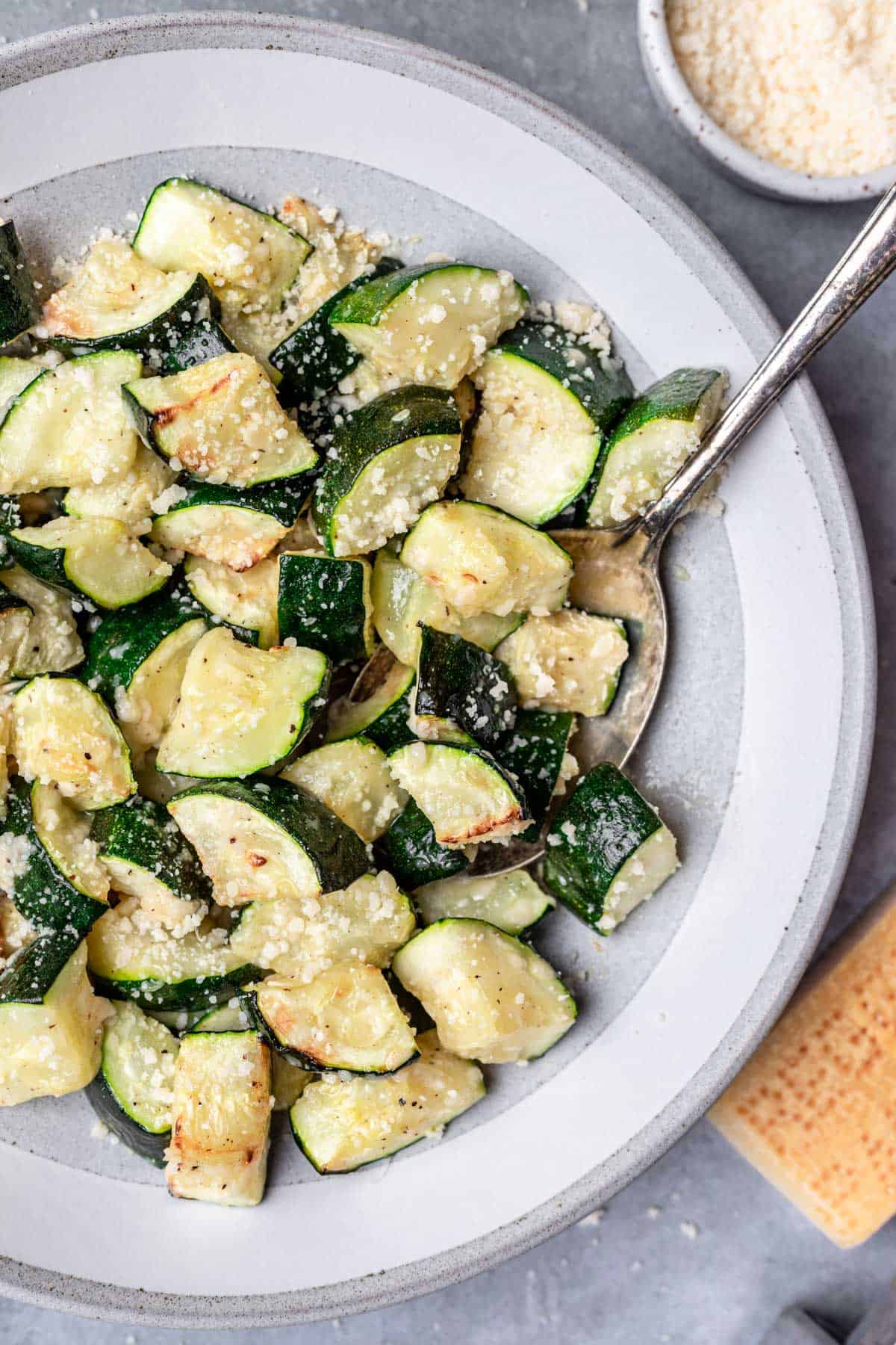Air fryer zucchini topped with parmesan cheese in a serving bowl.