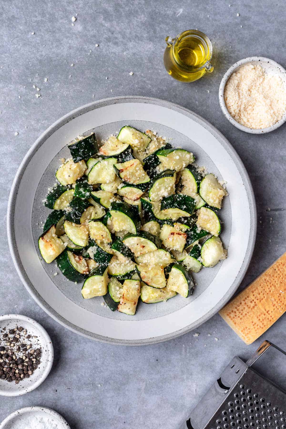 Air fryer zucchini in a serving bowl with a block of parmesan next to it.