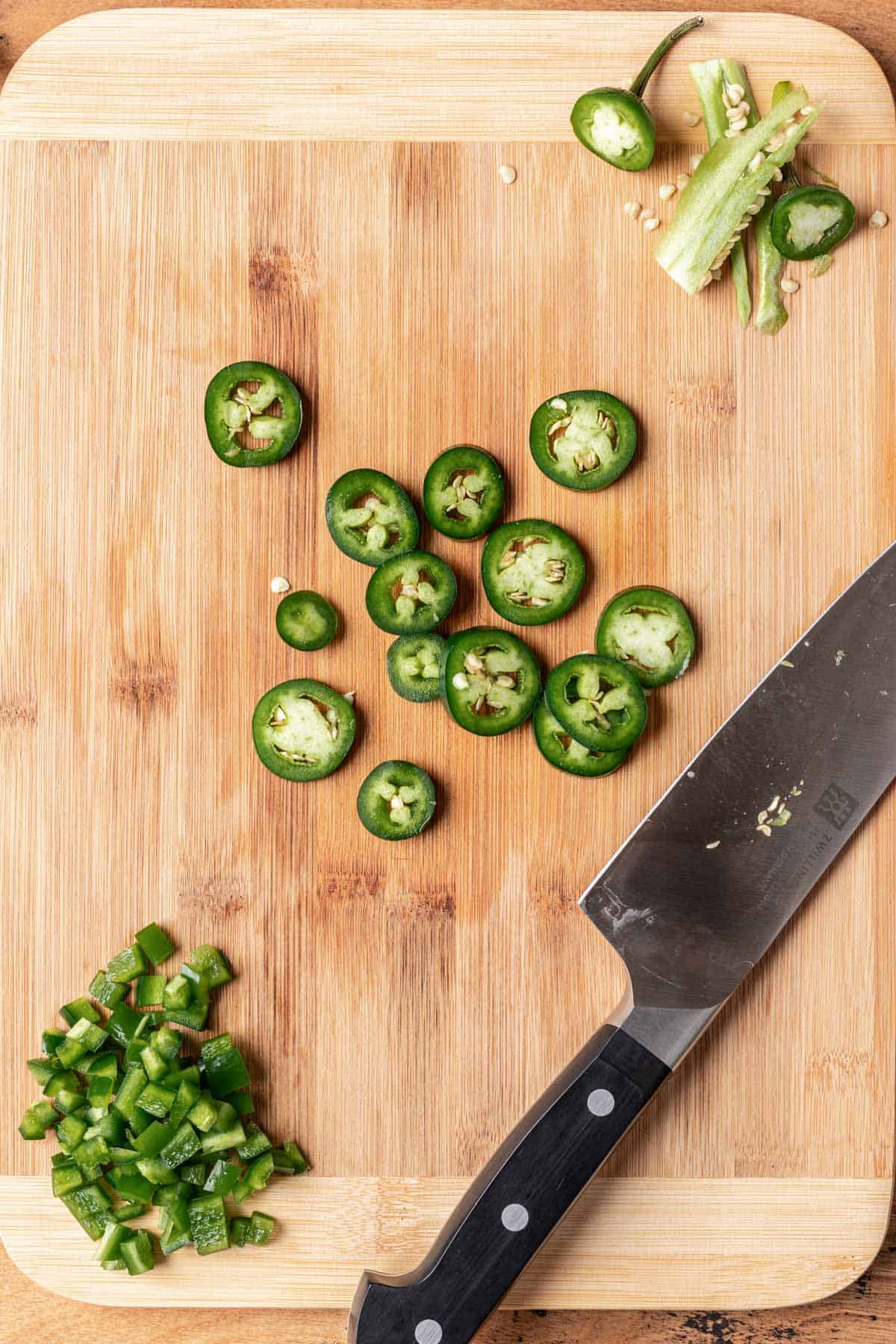 Sliced jalapeño in the middle of a wood cutting board.