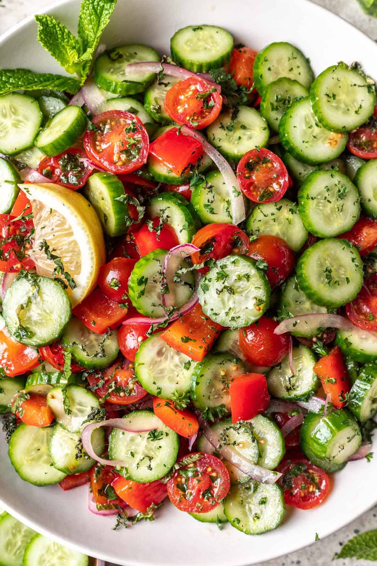 Jerusalem salad (israeli salad) mixed together with fresh parsley and mint garnished with lemon wedges.