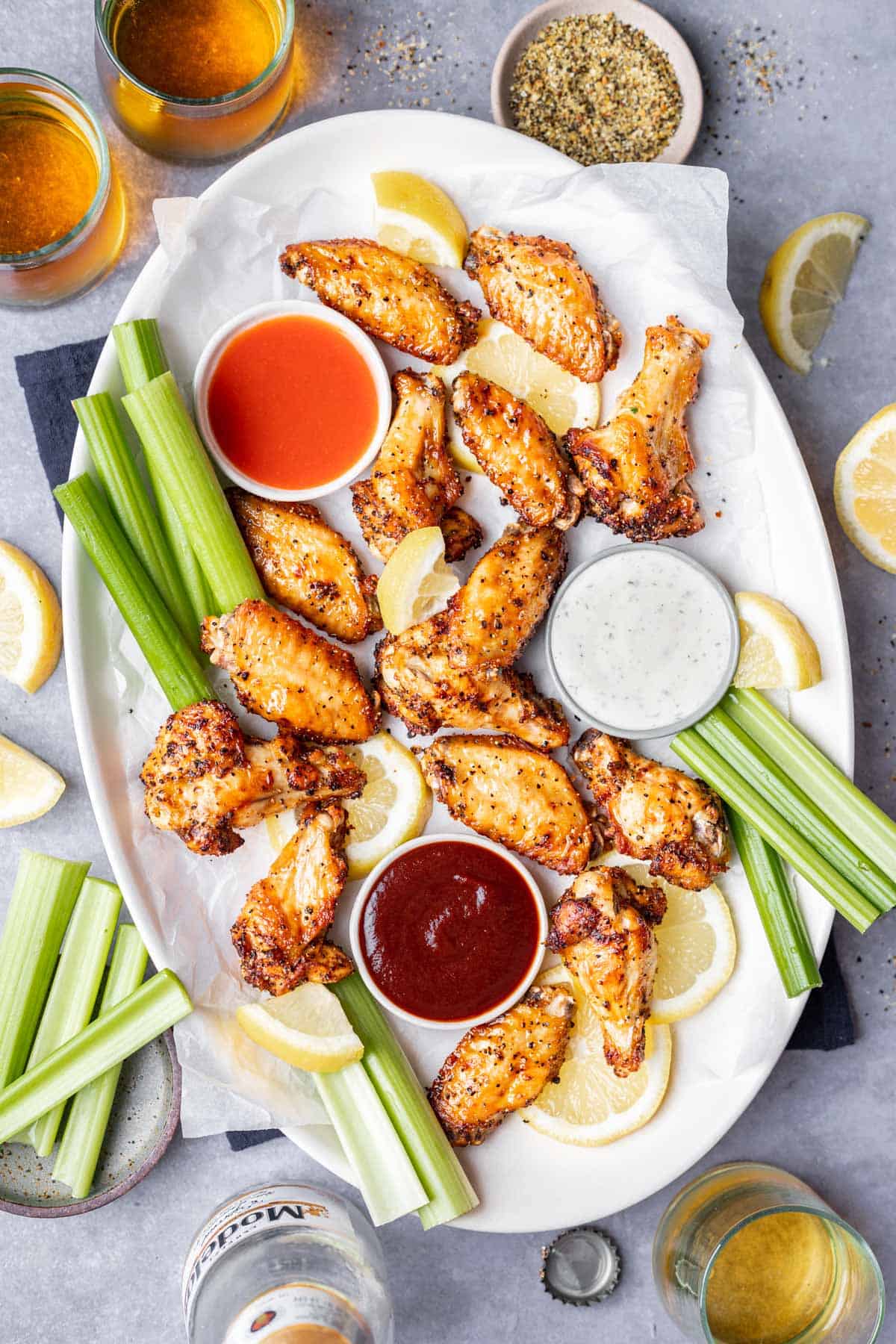 Air fryer lemon pepper wings on a serving platter with dipping sauces and celery.