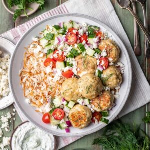 Greek chicken meatballs on rice pilaf with a cucumber and tomato salad.