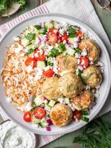 Greek chicken meatballs on rice pilaf with a cucumber and tomato salad.