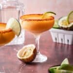 Passion fruit margarita in a coupe glass with a lime slice and a halved passion fruit.