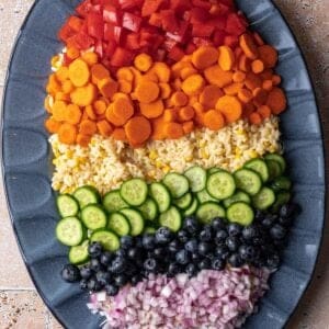 Rainbow orzo salad with pesto on a blue serving platter.