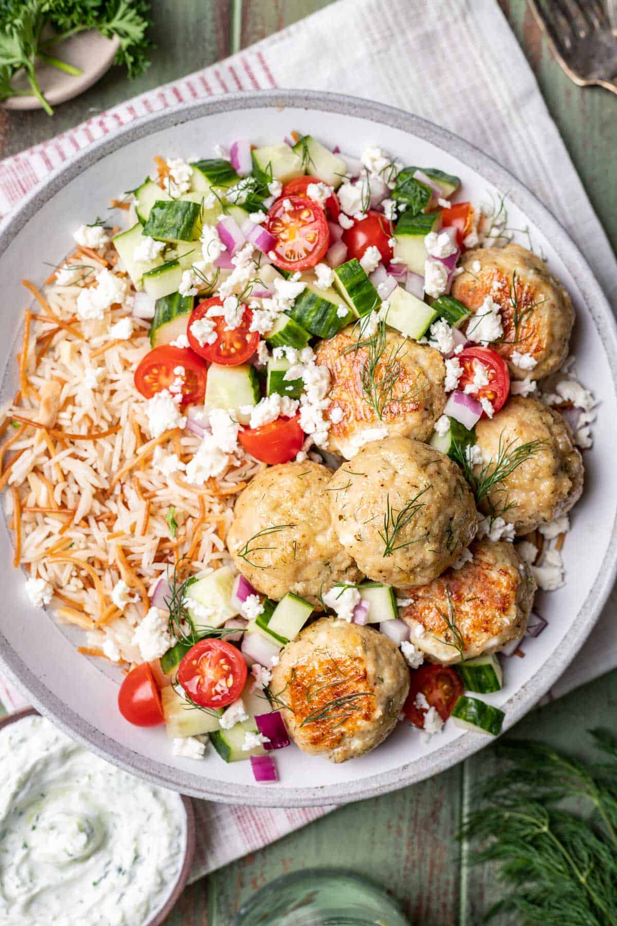 Greek chicken meatballs on rice pilaf with a cucumber and tomato salad.
