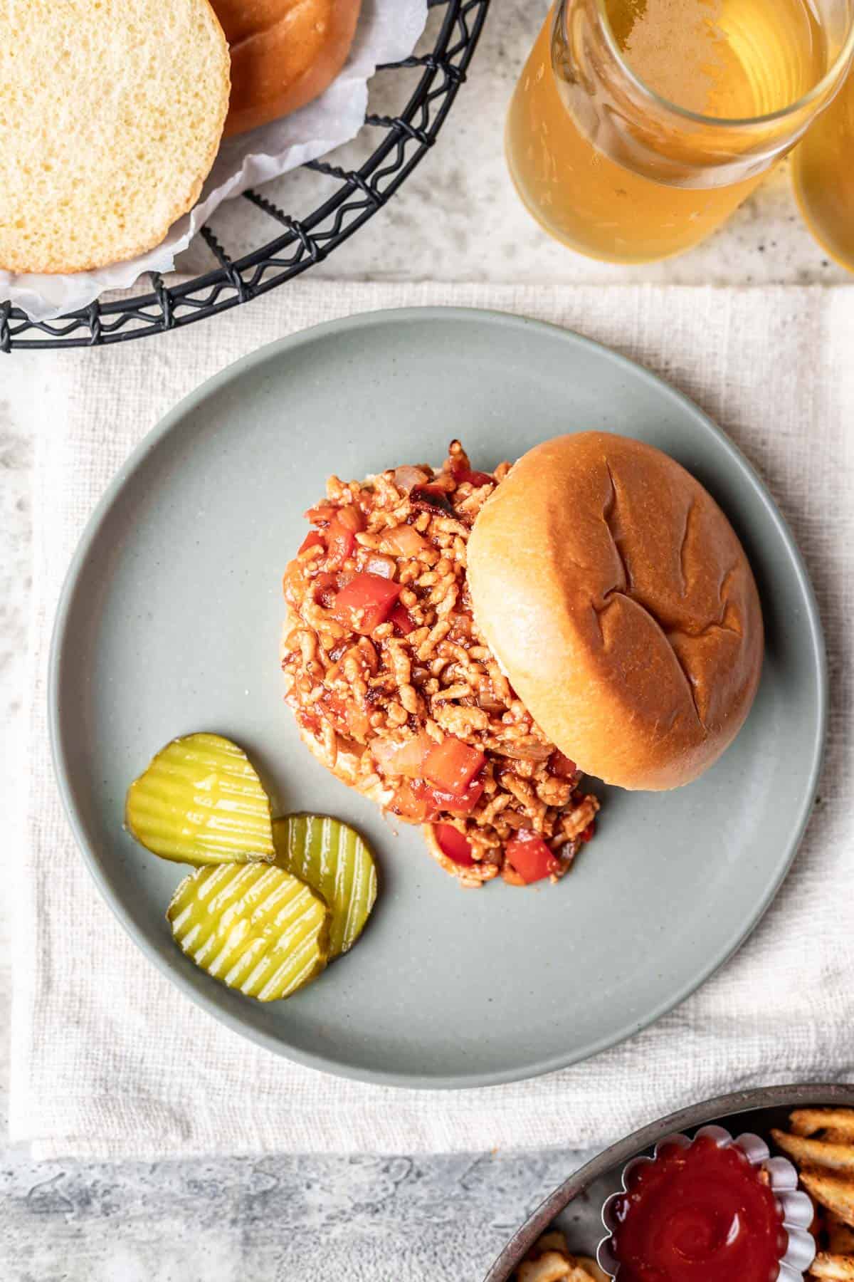 A chicken sloppy joe with on a plate with waffle fries in a dish to the side.