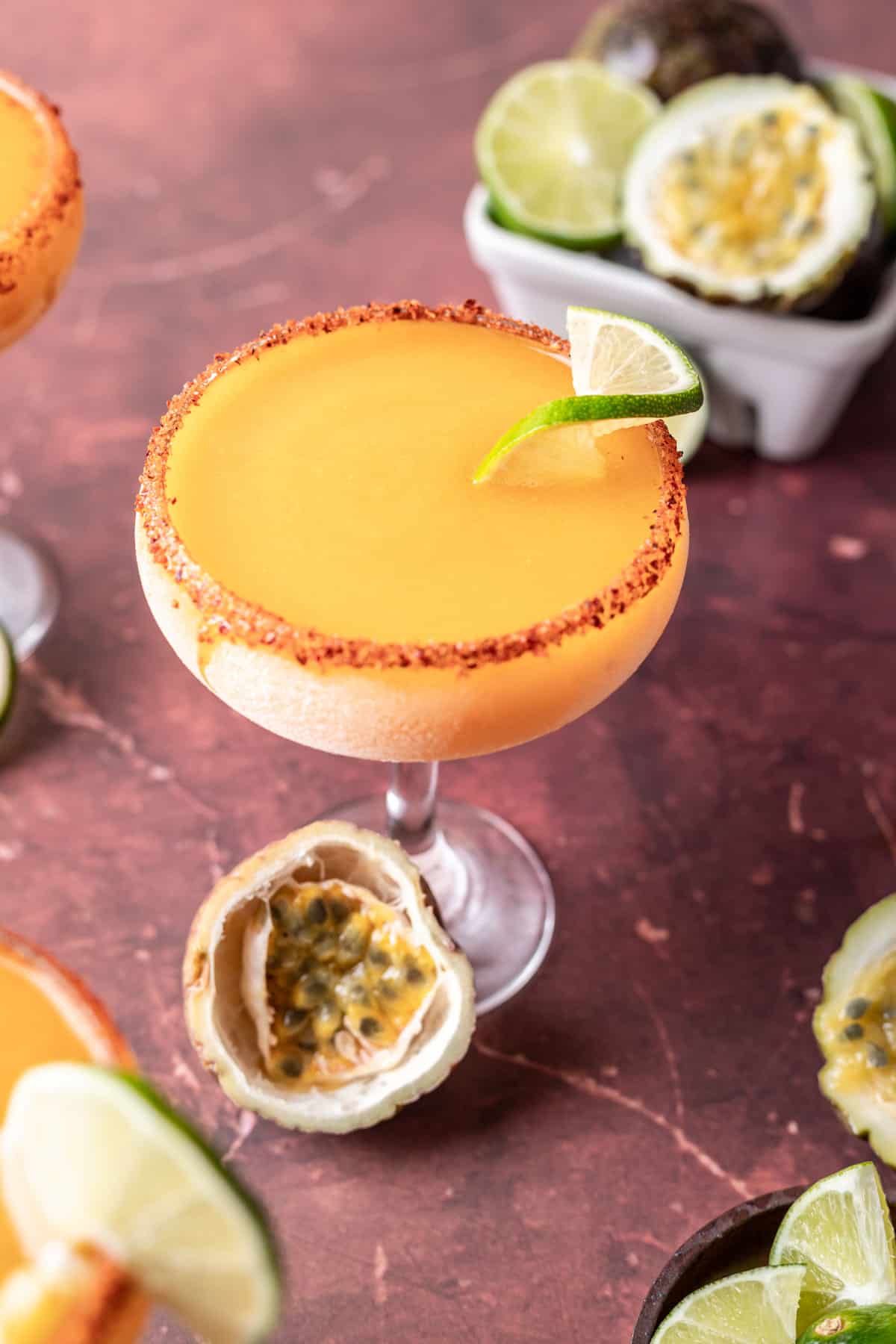 Frozen passion fruit margaritas in a glass with lime slices and fresh passion fruit.