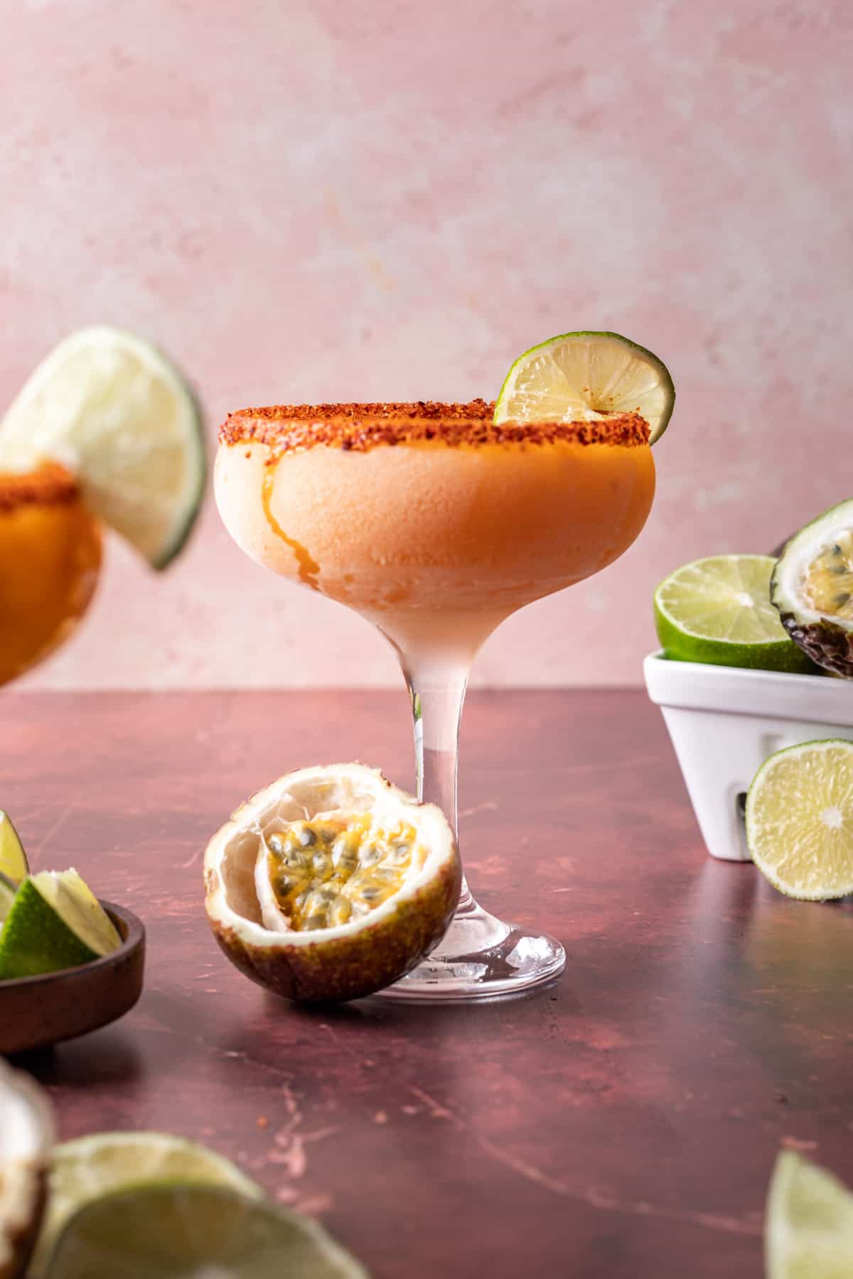 Frozen passion fruit margaritas in a glass with lime slices and fresh passion fruit.