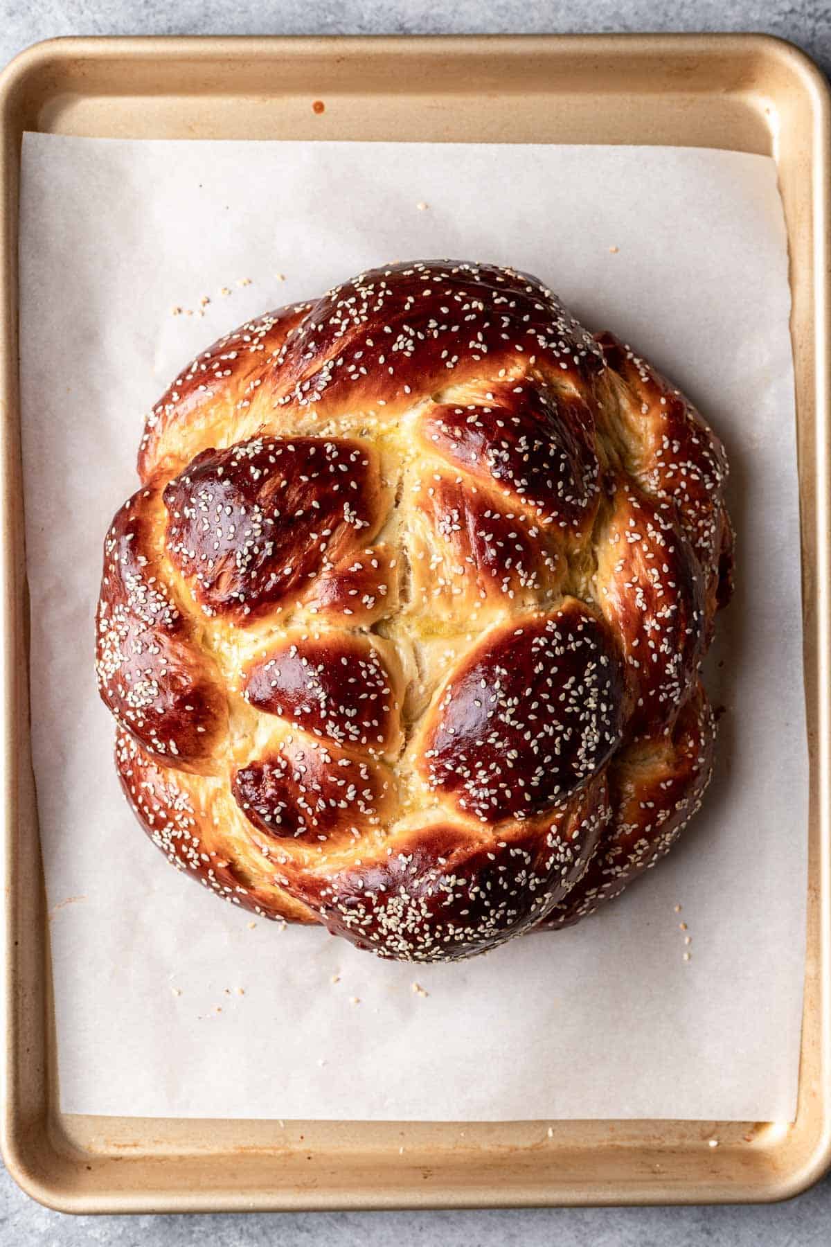 Perfectly browned round challah on a baking sheet right after baking.