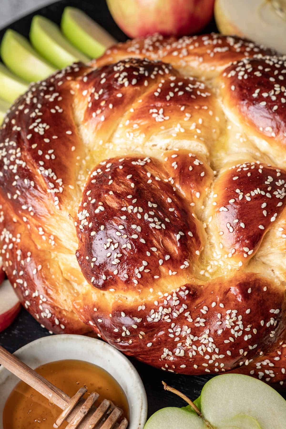 Round challah served with apple slices and honey for rosh hashanah.