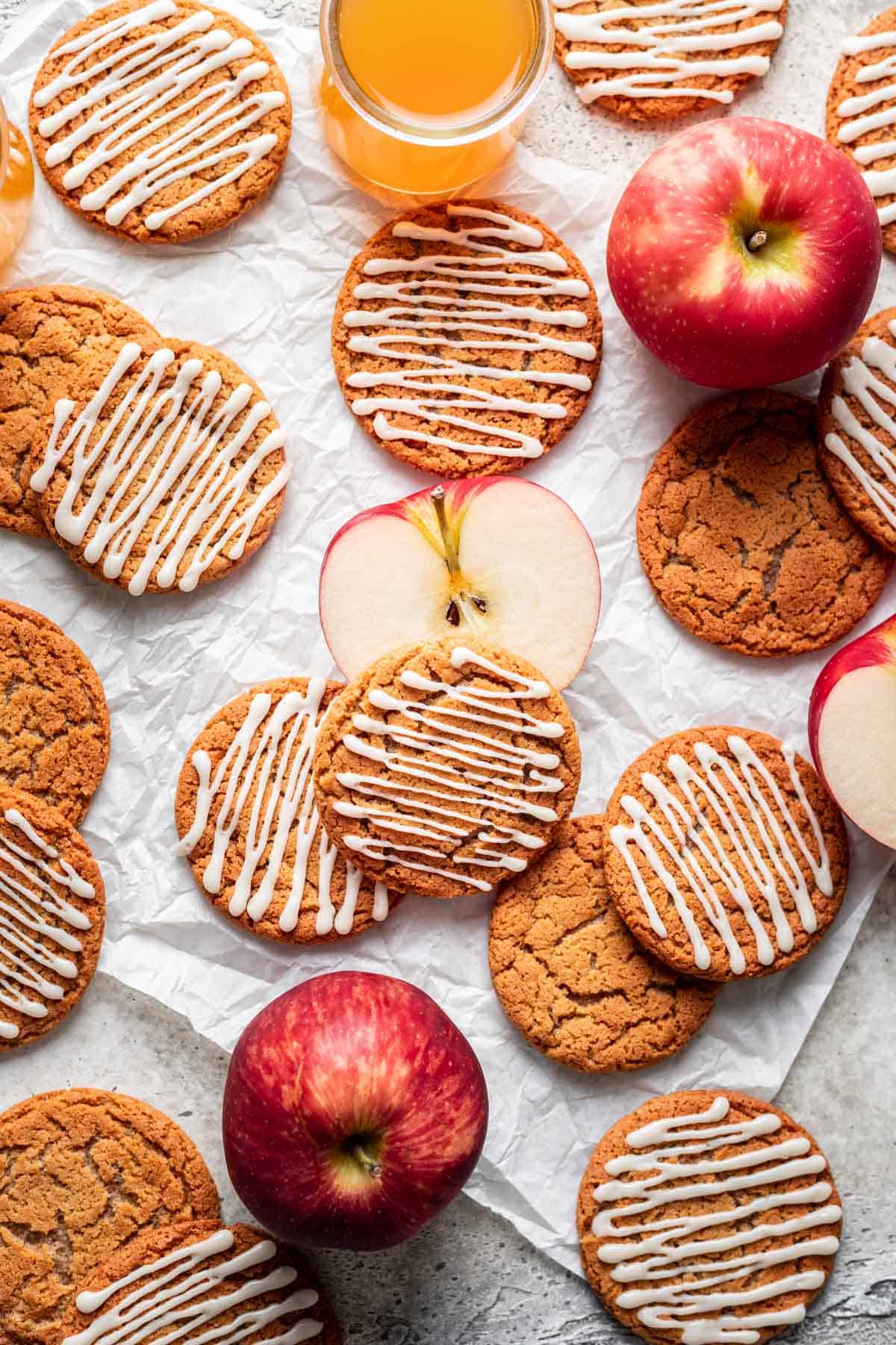 Chewy apple cider cookies on parchment paper with apples around them.