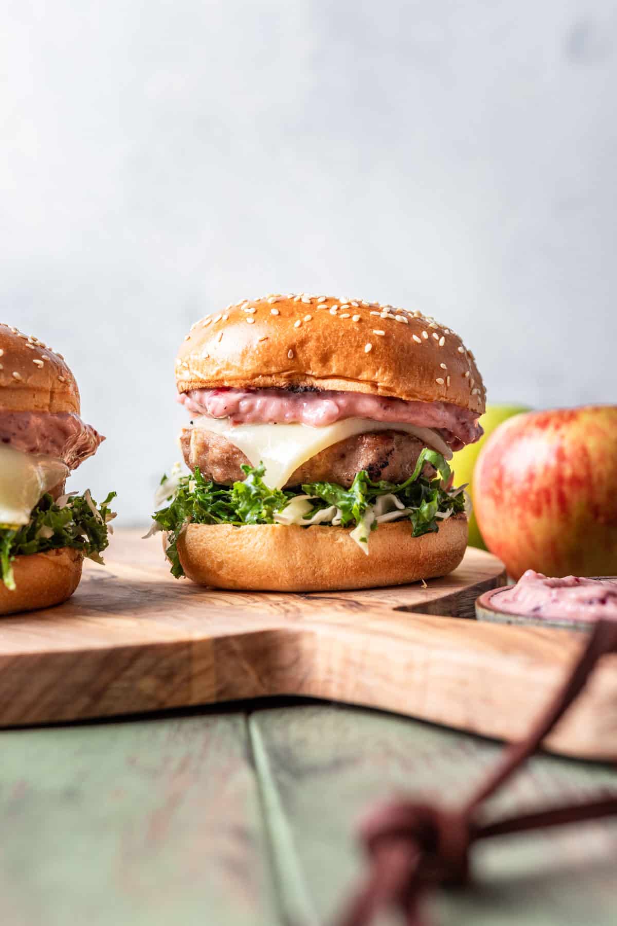 Apple turkey burger on a sesame brioche bun with apples next to it.