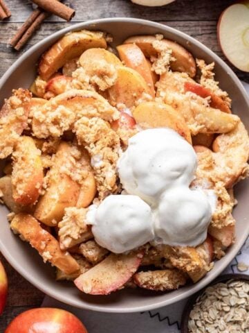 Air fryer apples in a serving bowl with scoops of ice cream on top.