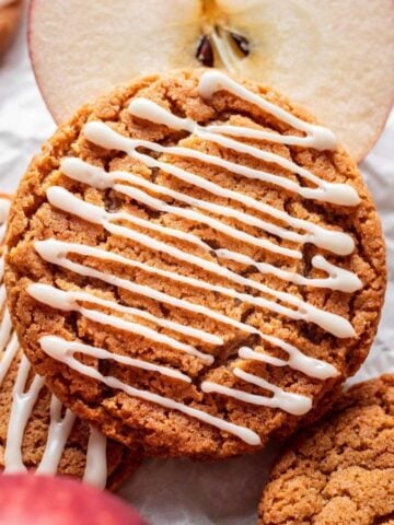 Apple cider cookie resting on a sliced apple.