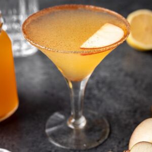 Apple cider martini garnished with ground cinnamon and an apple slice.