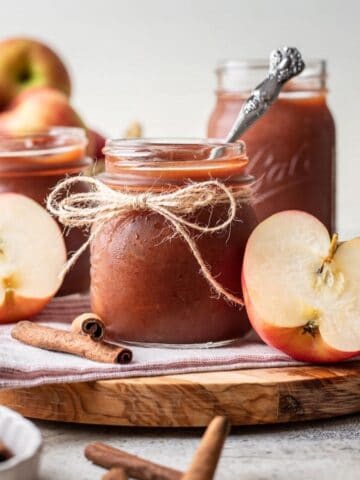 Instant pot apple butter in a glass jar with a spoon.