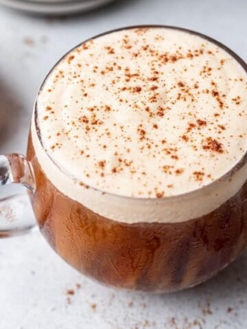 Pumpkin cream cold foam in a glass mug dusted with pumpkin pie spice over top.