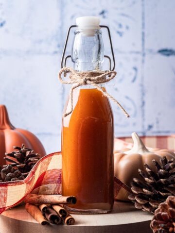 Pumpkin spice simple syrup in a bottle on a serving tray.