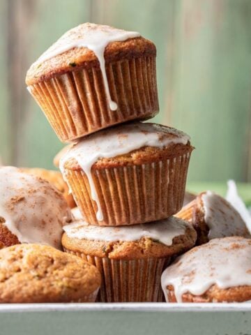 Pumpkin zucchini muffins stacked on top of each other.