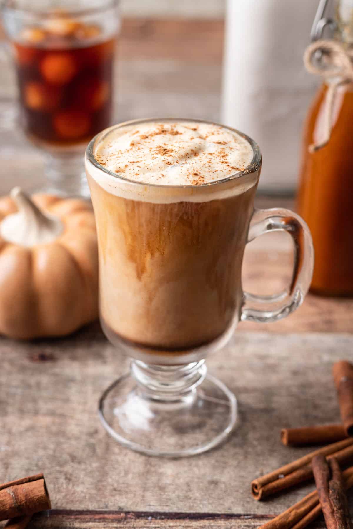 Iced pumpkin spice latte in a glass mug topped with pumpkin cold foam.