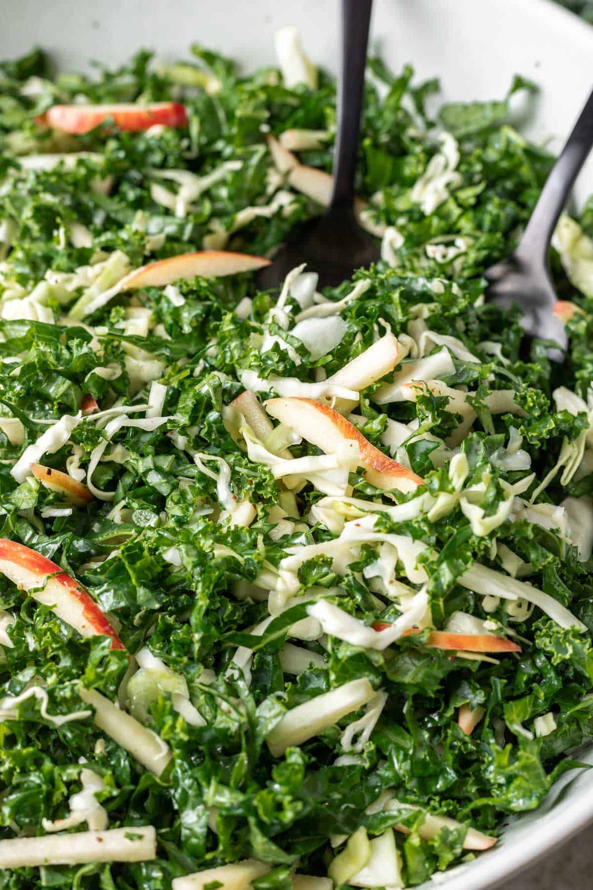 A close up of kale apple slaw with thinly sliced apples.