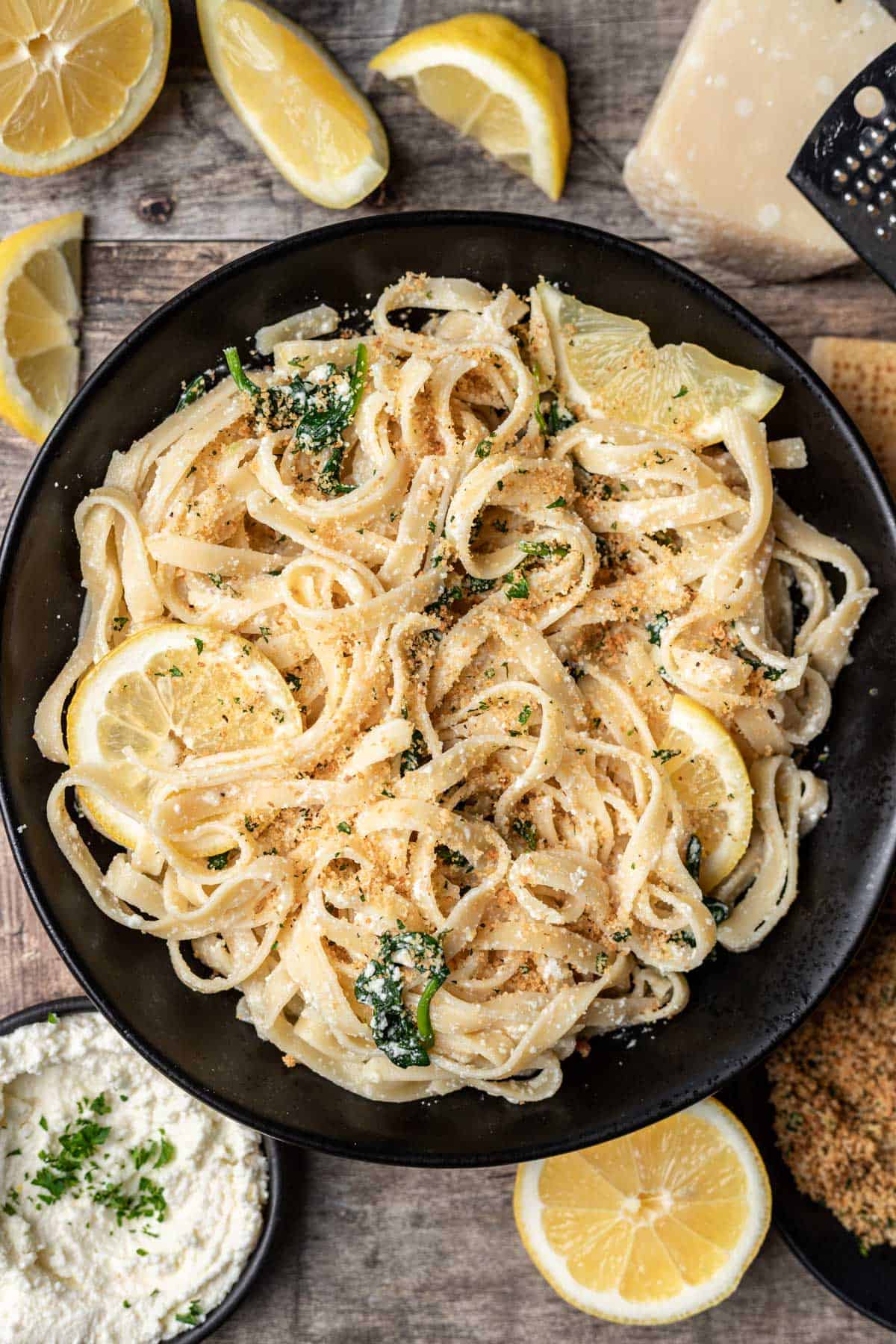 Lemon ricotta pasta in a black serving bowl with lemon slices.