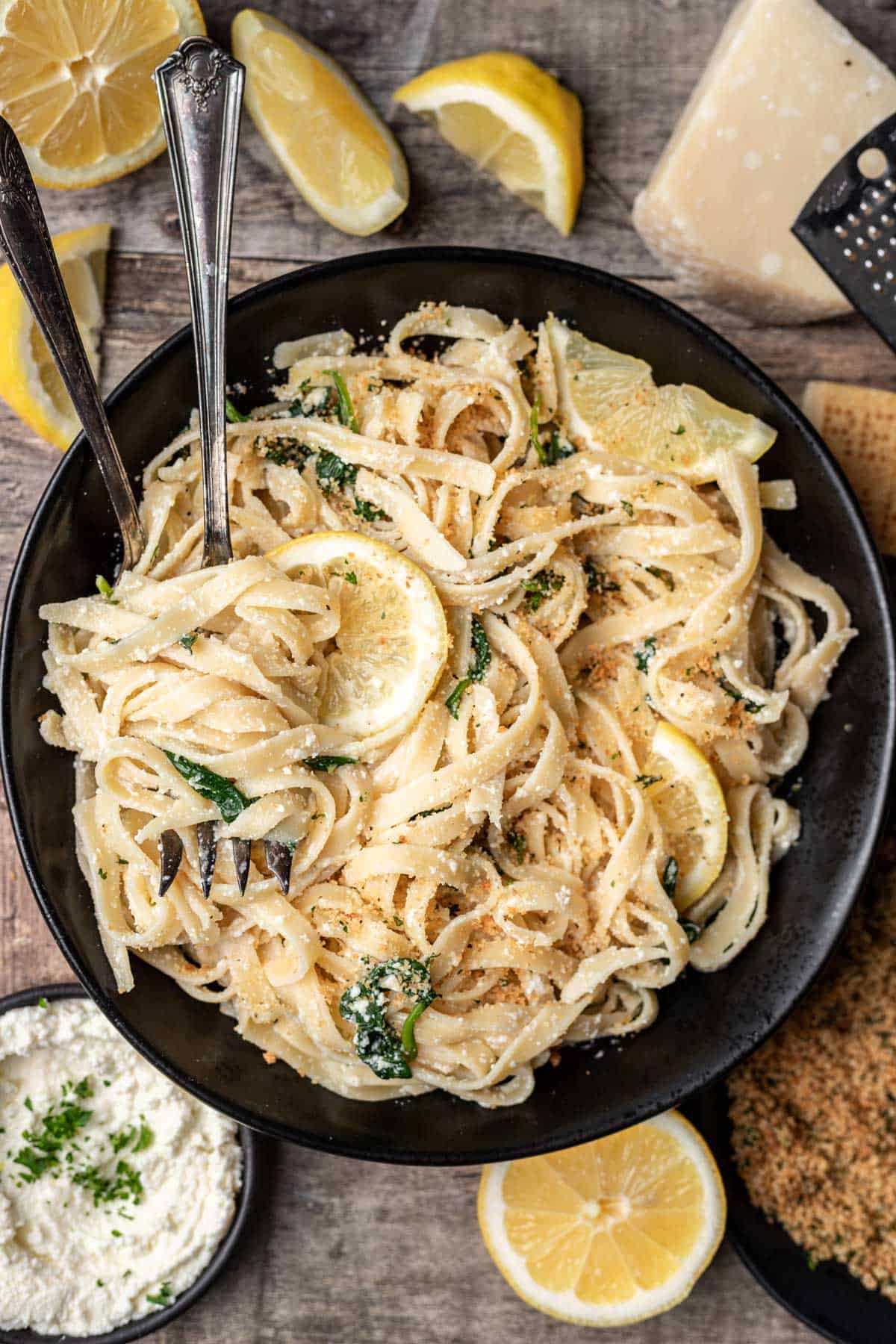 One pot lemon ricotta pasta in a black bowl with two serving forks.